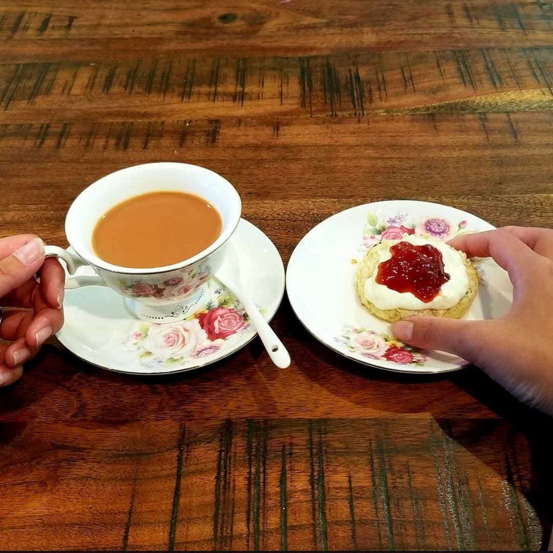 drinking tea with Britalicious scone and clotted cream and jam